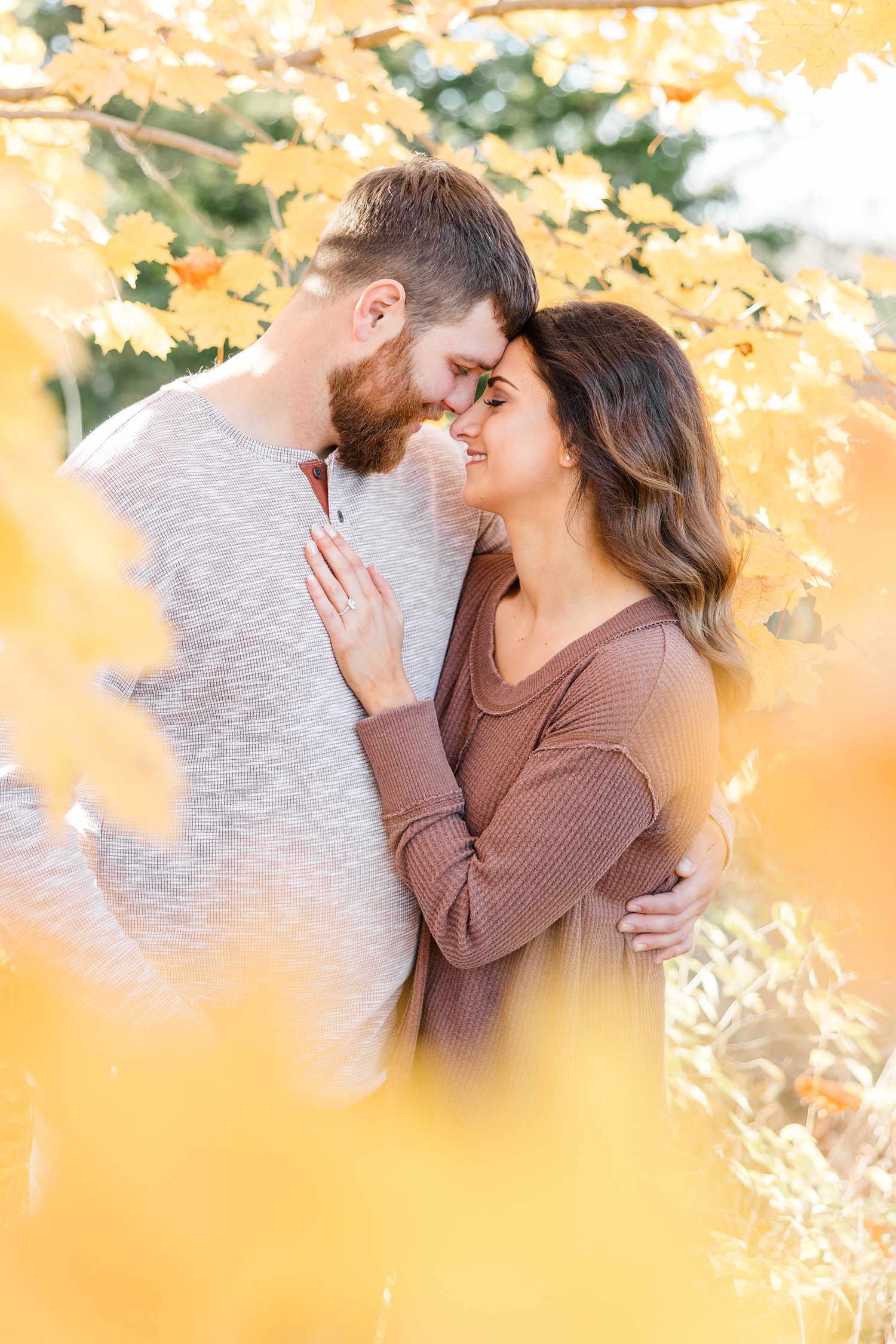 Kylie and Drake embrace and rest their foreheads together while surrounded by yellow maple leaves in the height of fall season | CB Studio