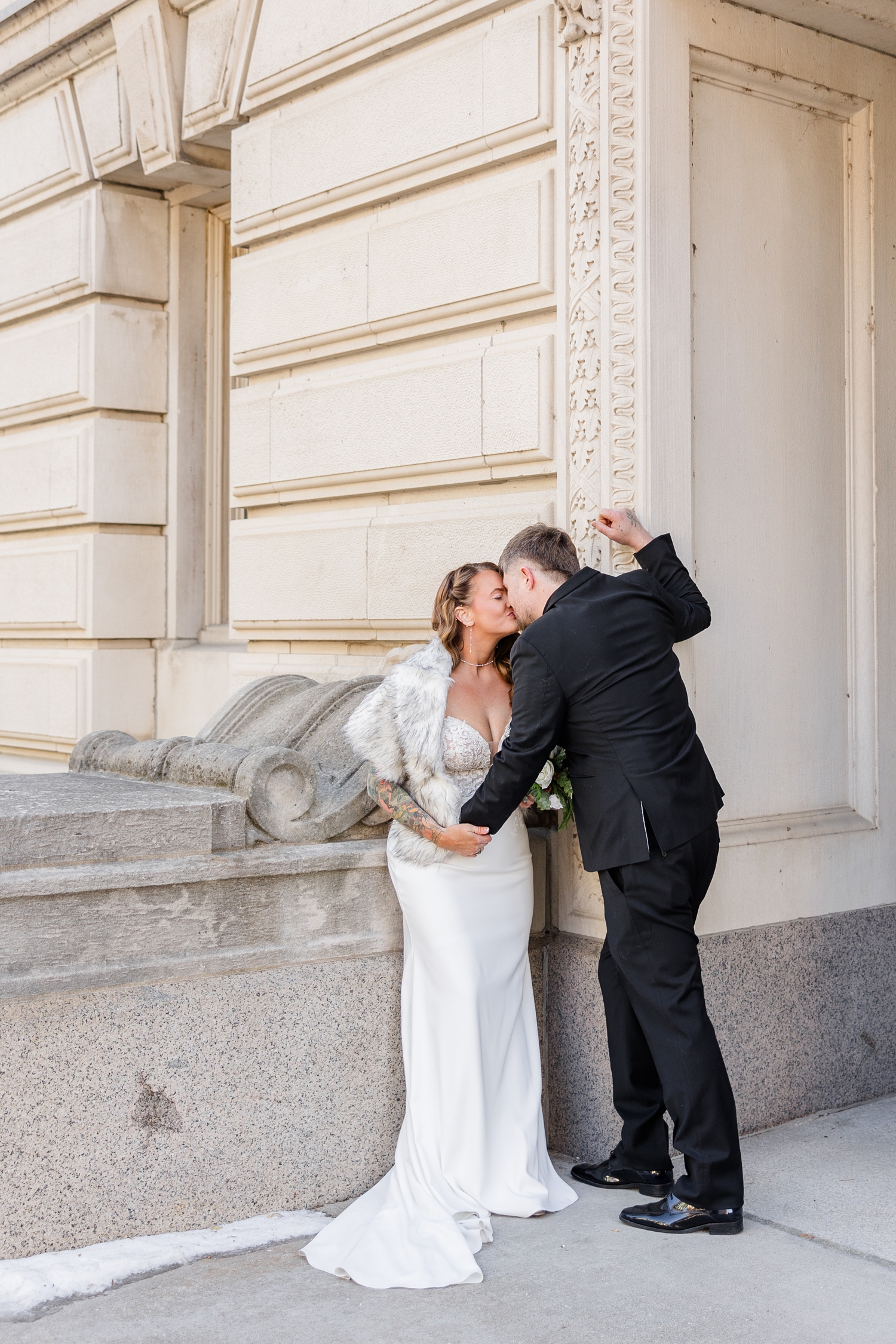 Lisa leans on a beautiful architectural wall of the Polk County Courthouse as her new groom, Chris, leans in to kiss her | CB Studio