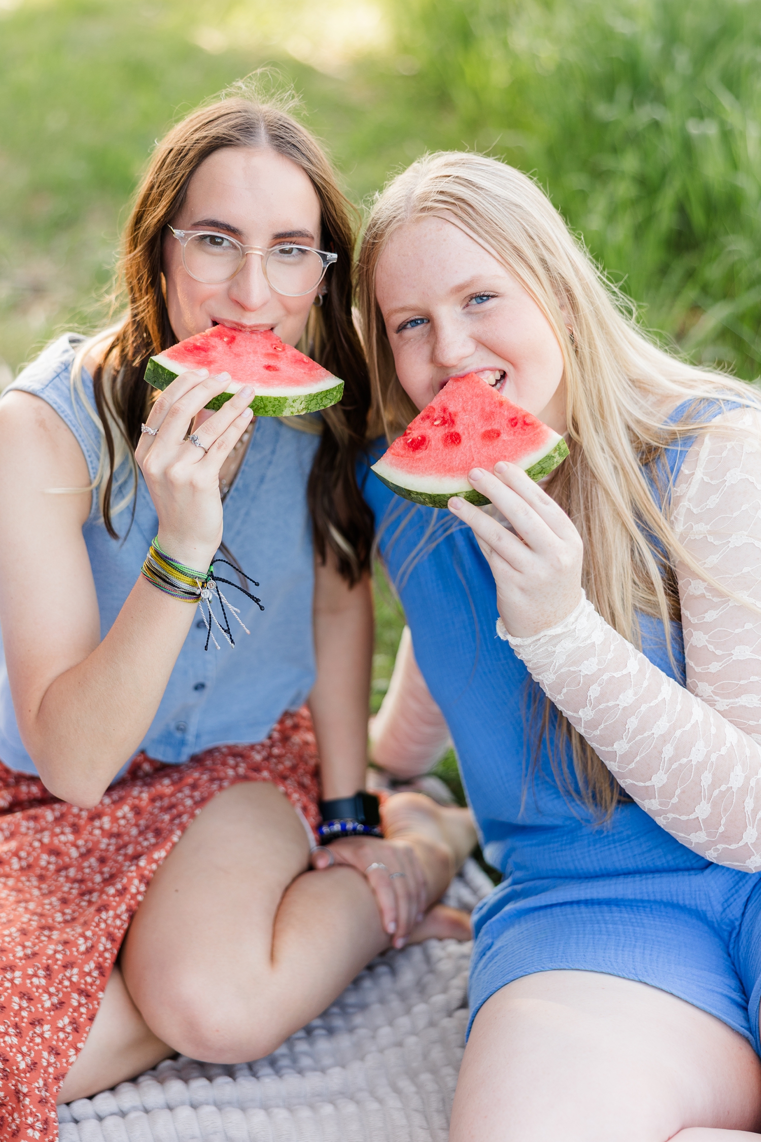 Rose and Ashtyn sit on a blanket in a grass field for a picnic and both take a bite of watermelon at the same time | CB Studio
