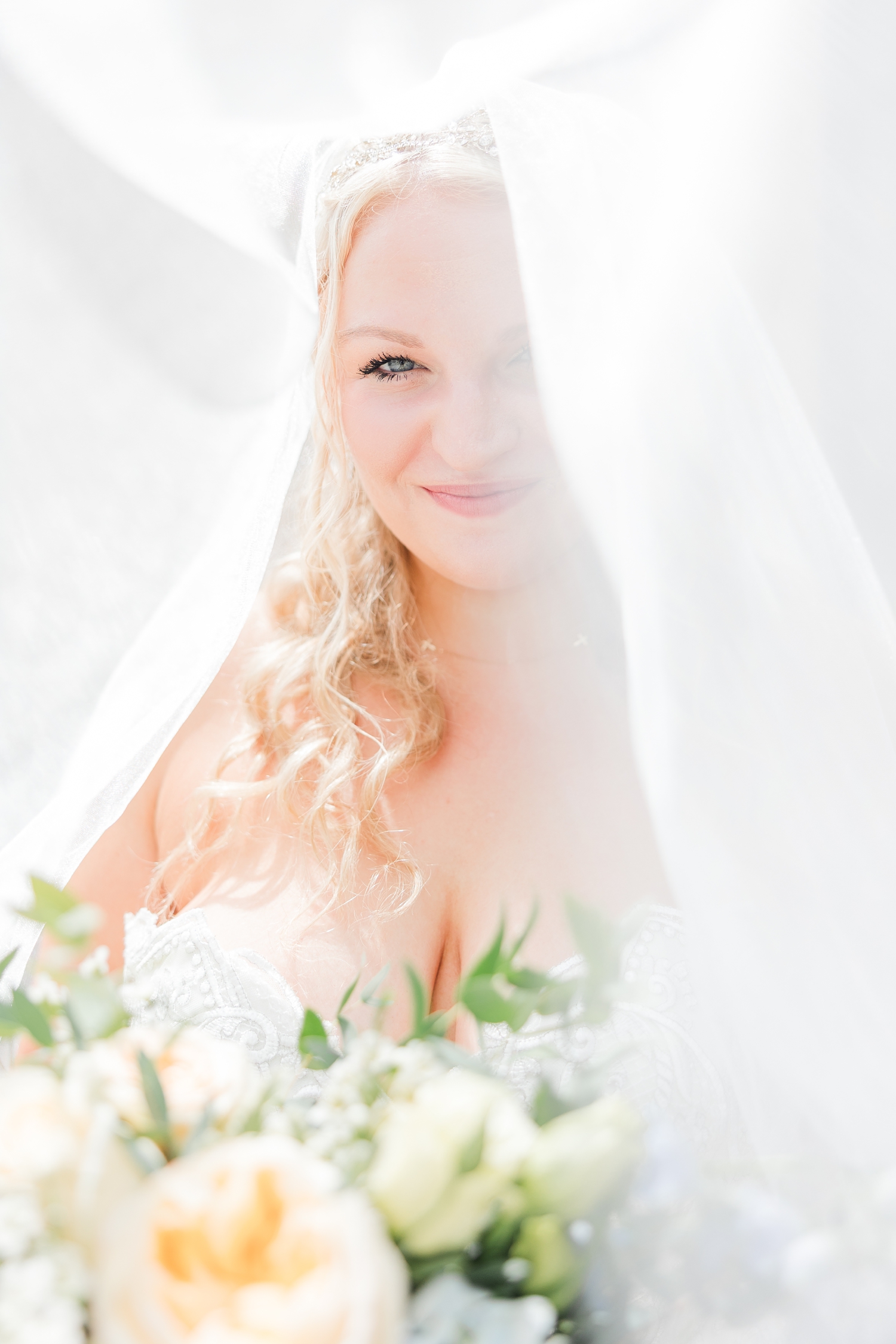 Natalie peeks through her blusher veil to reveal just one of her eyes with her wedding bouquet in the foreground | CB Studio