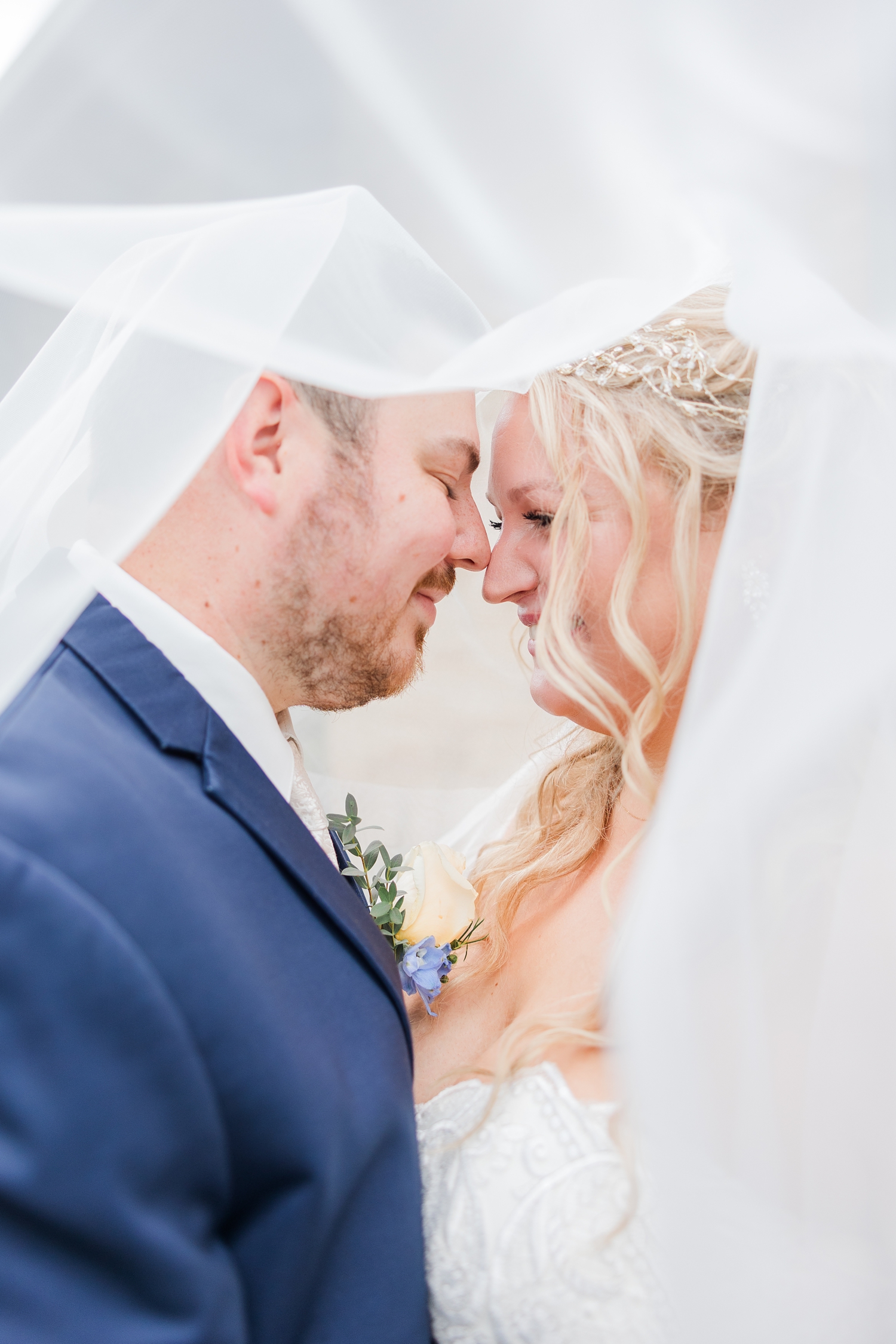 Natalie and Connor rest noses together as they are engulf under Natalie's blusher veil | CB Studio