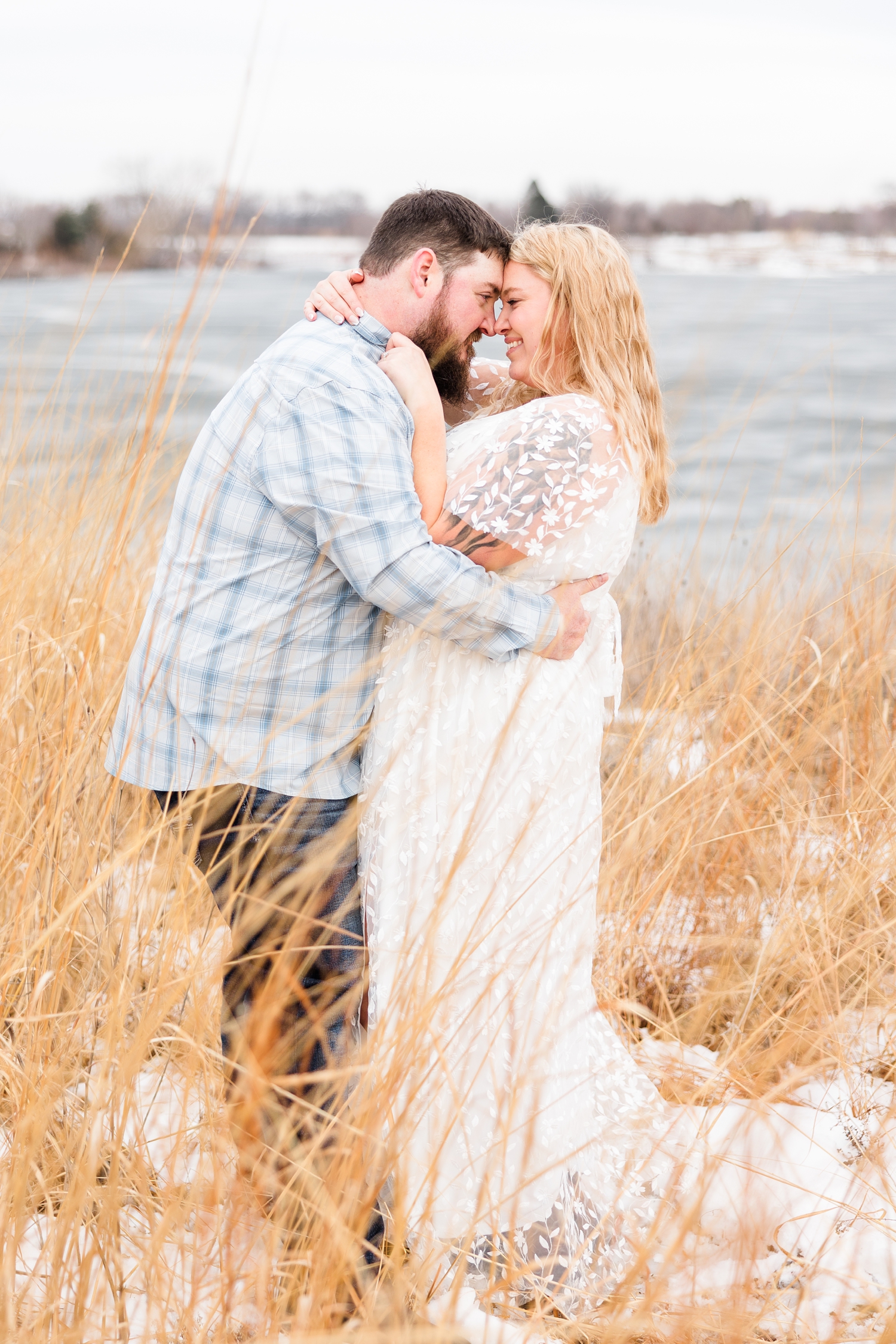 Dalton and Teri embracing and resting foreheads together with Smith Lake in the background at Water's Edge Nature Center during early spring in Iowa | CB Studio