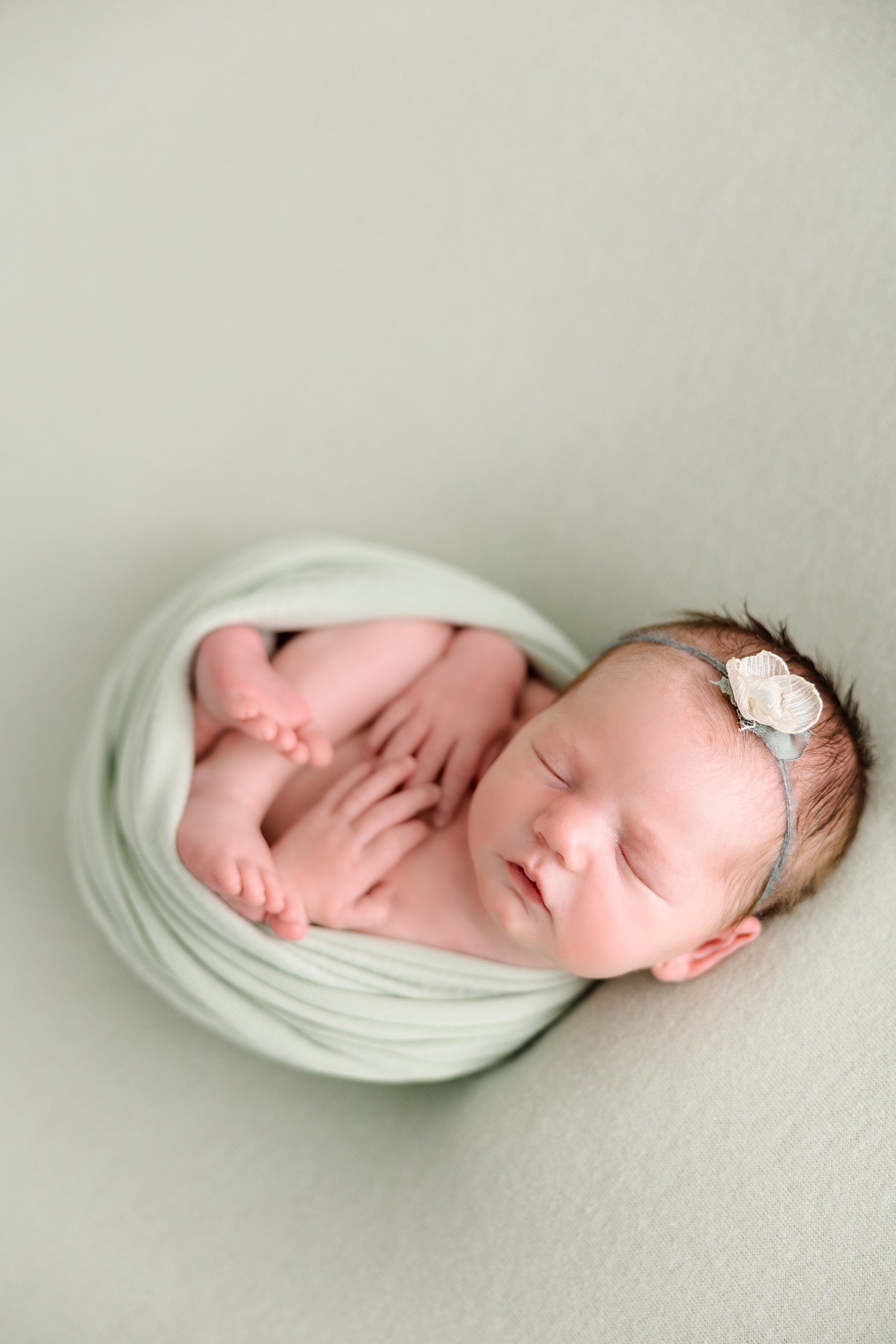 Baby Parker wrapped in green with hands and feet visible laying on an all green backdrop | CB Studio 