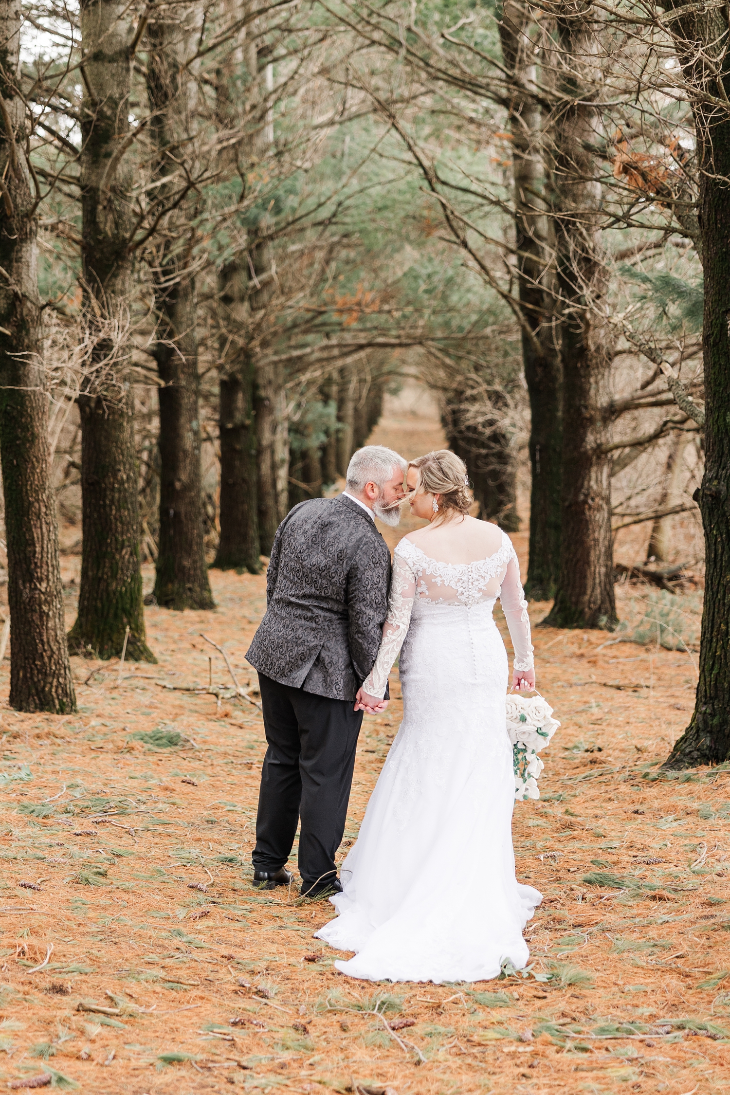 Nick and Sydney rest foreheads together as they walk in the middle of the narrow pathway beneath the pines of the Water's Edge Nature Center | CB Studio