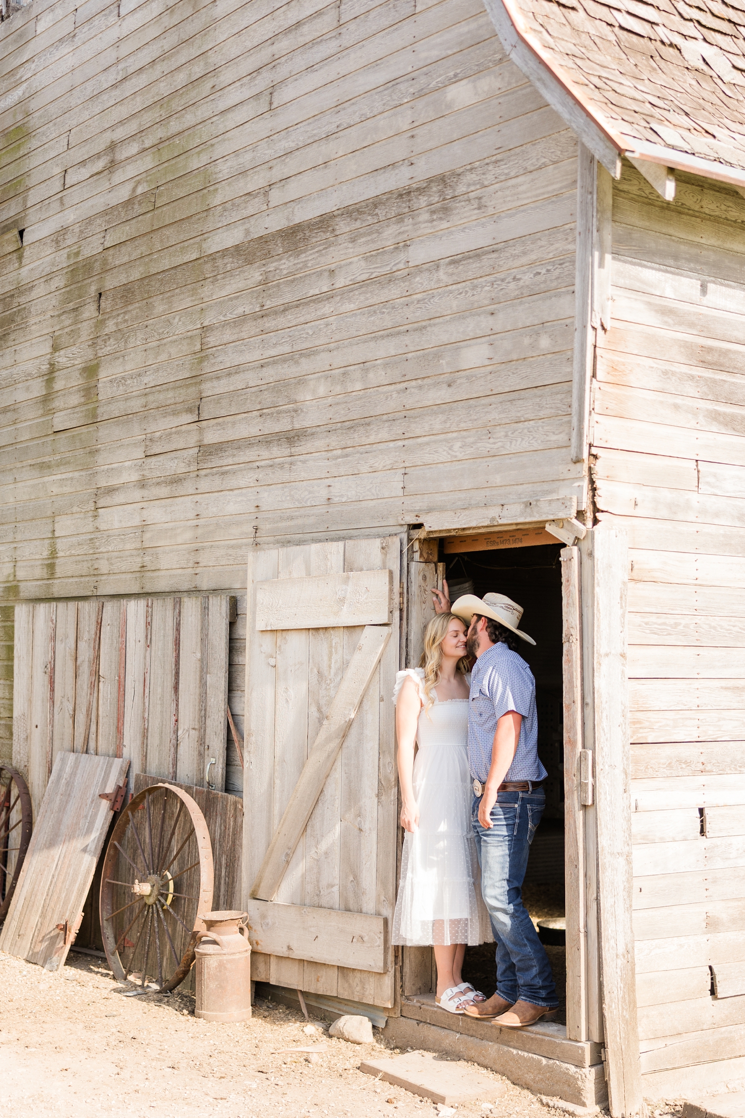 Dawson and Jade stand in the doorway of an old wooden barn as Dawson leans in to give Jade a kiss | CB Studio