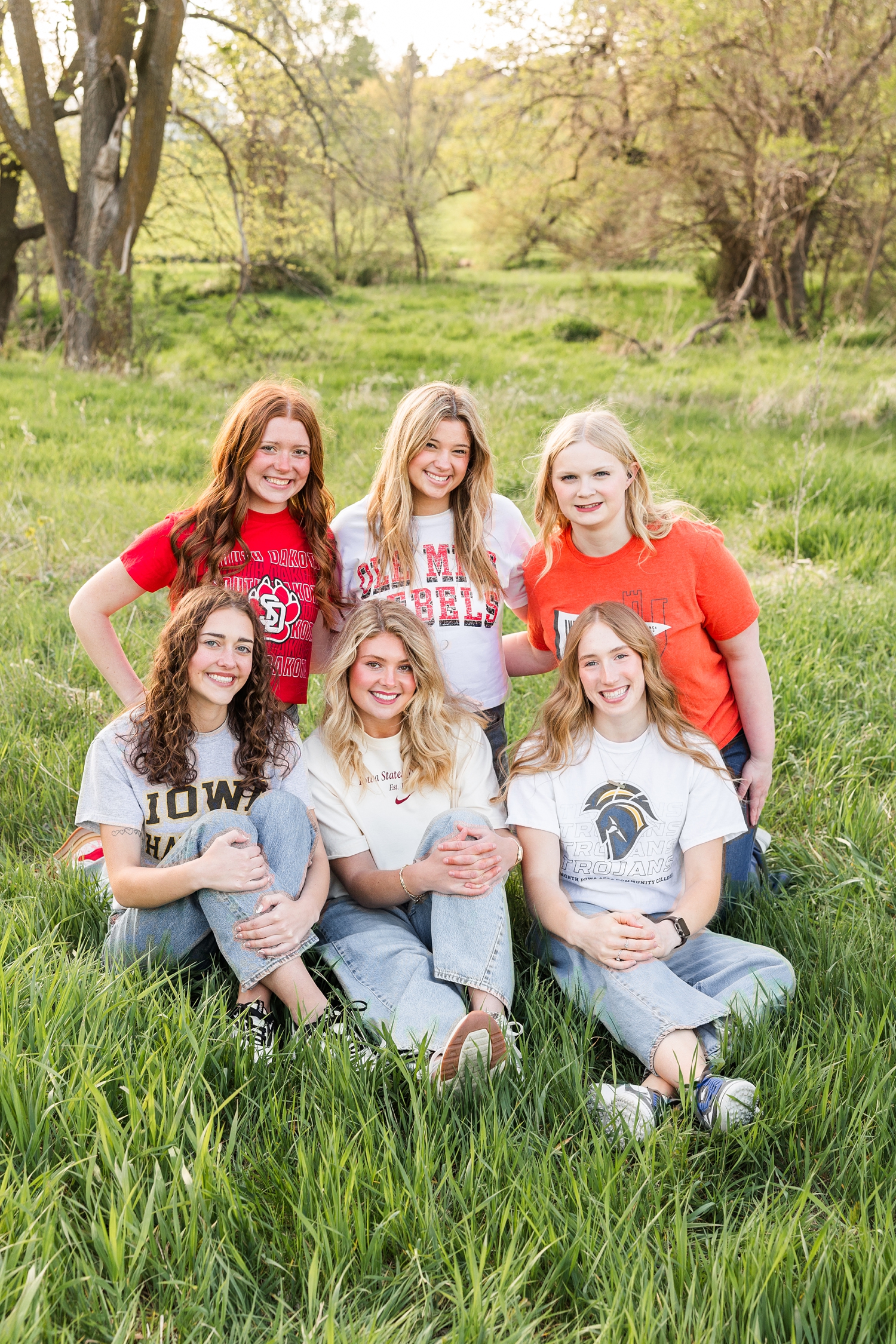 TEAM 26 sit and squat in the pasture grass wearing their college t-shirts | CB Studio