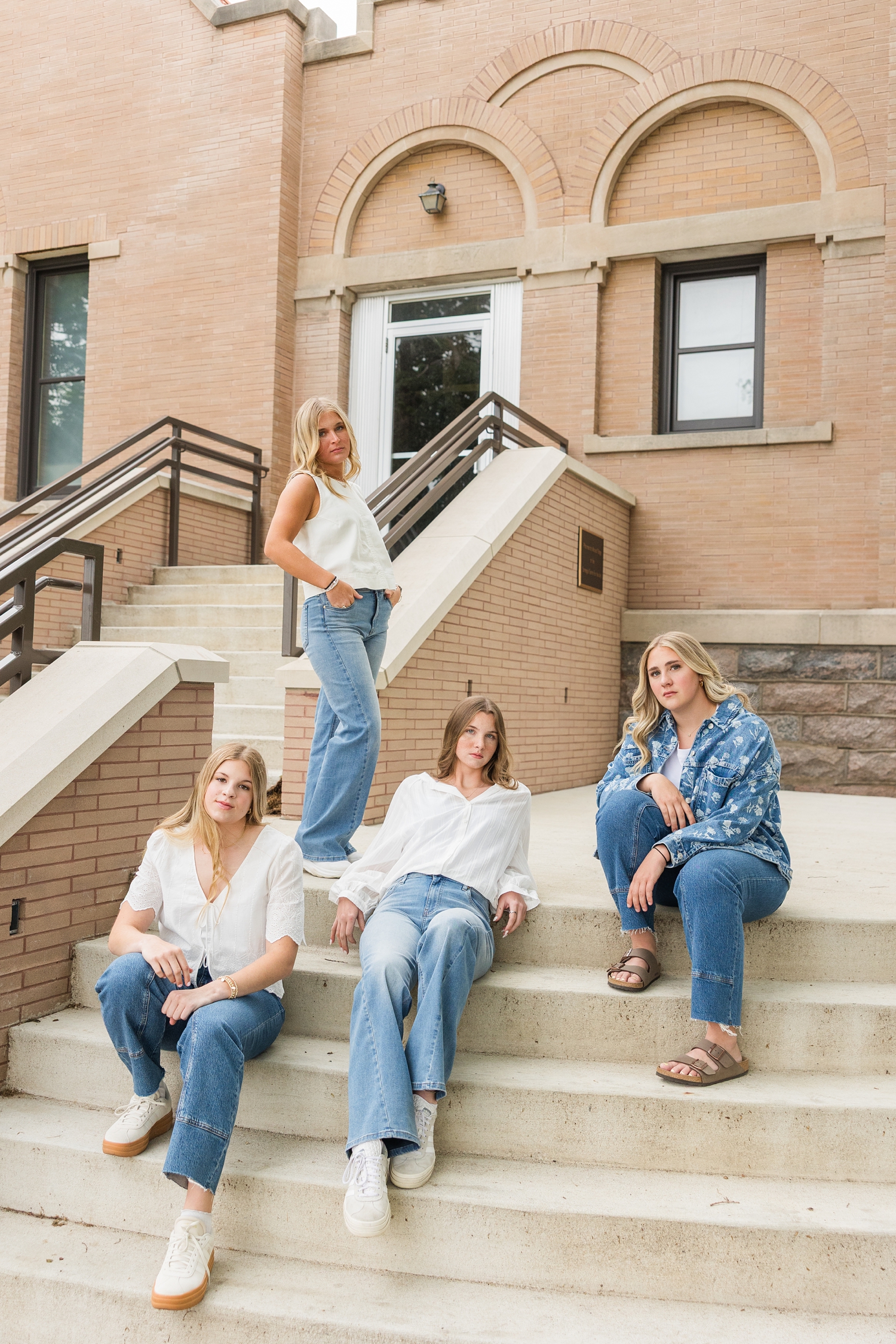 TEAM 27 dressed denim styles, pose staggered along the front steps of the Carnegie Library in Algona, IA | CB Studio