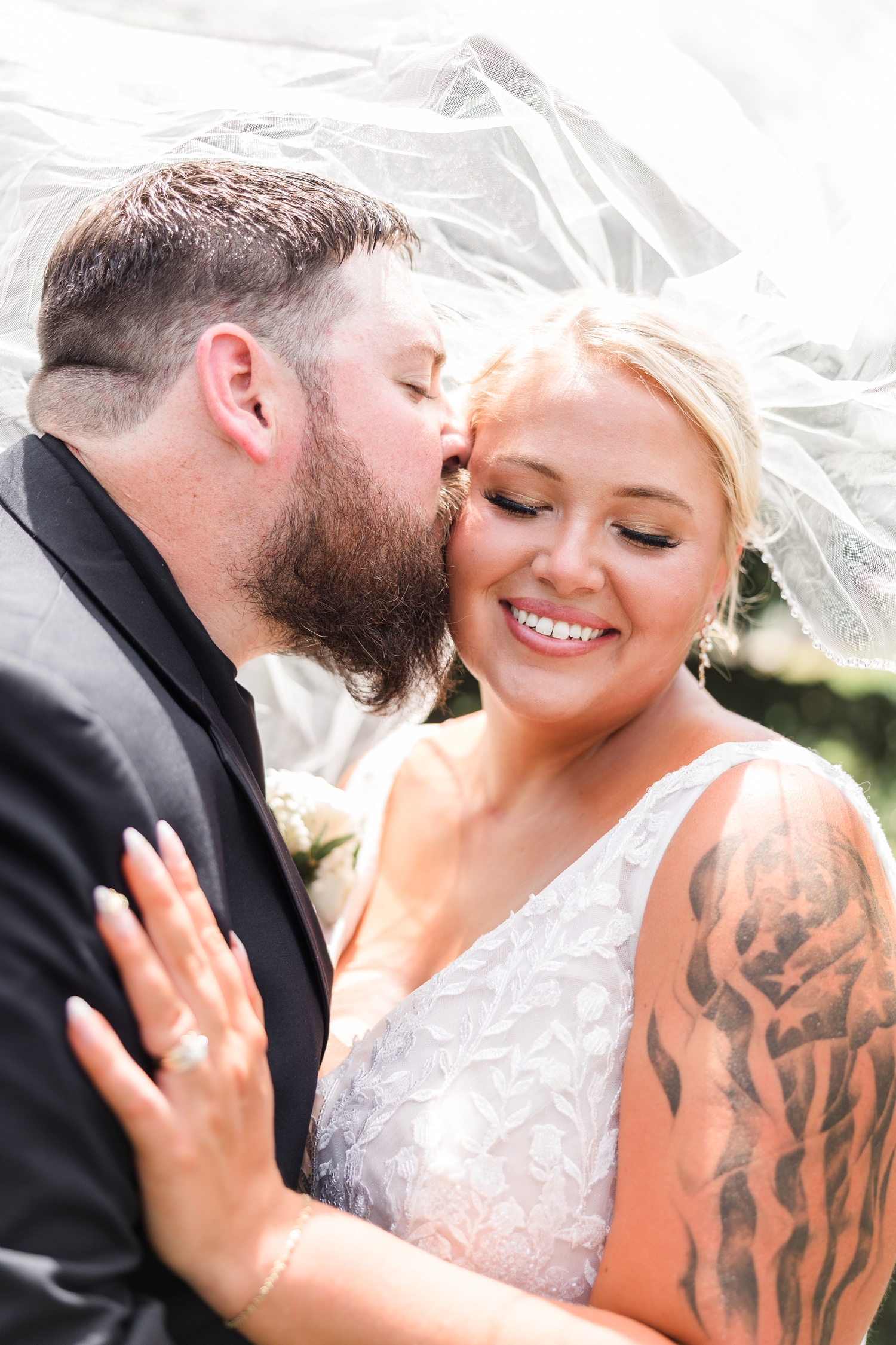 Dalton kisses Teri's cheek as they both embrace each other underneath Teri's wedding veil | CB Studio