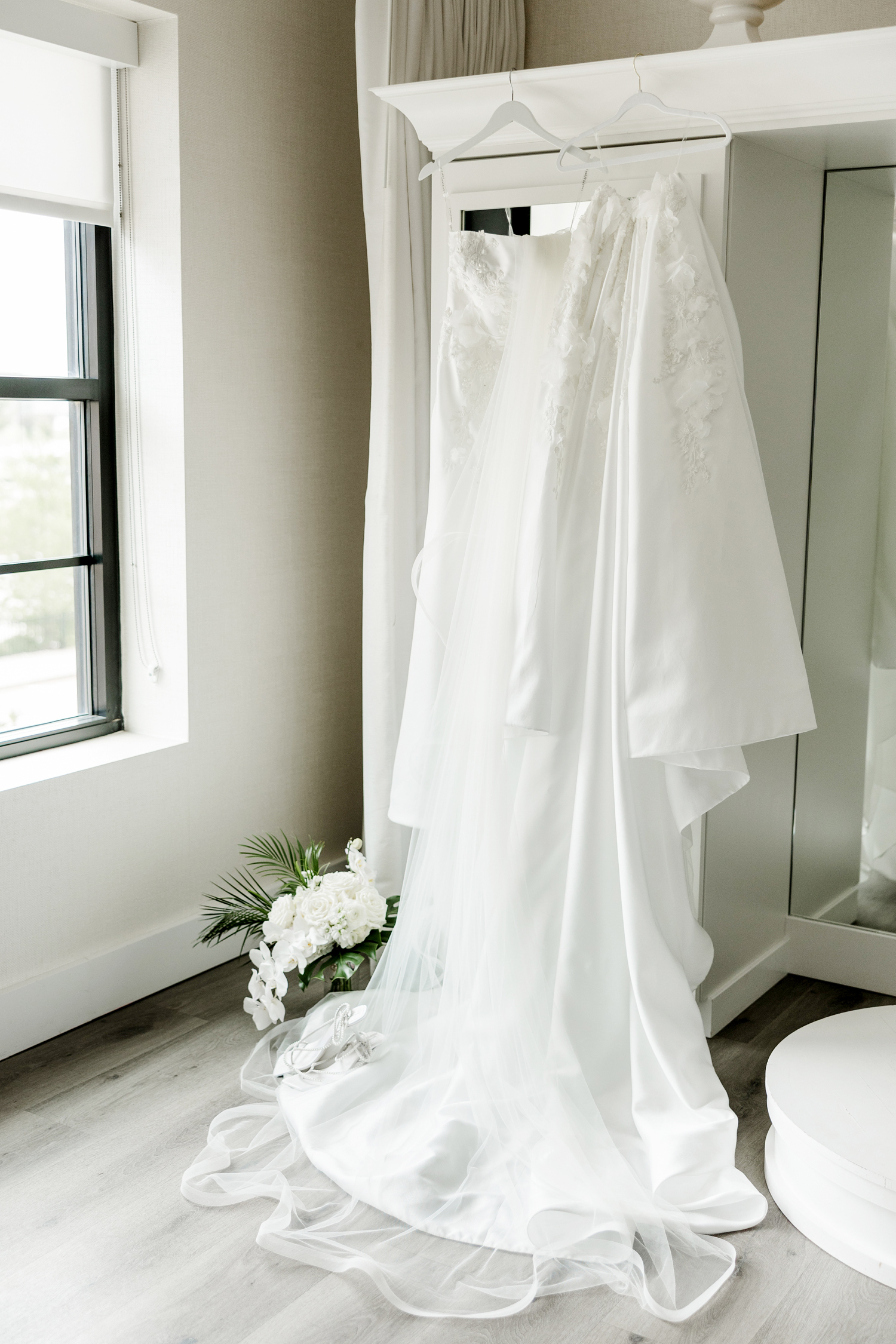 Cassidy's Eva Lendel wedding dress hangs from the white built-in dressing pedestal/closet in the all-white bridal suite at Toast Ankeny, IA | CB Studio