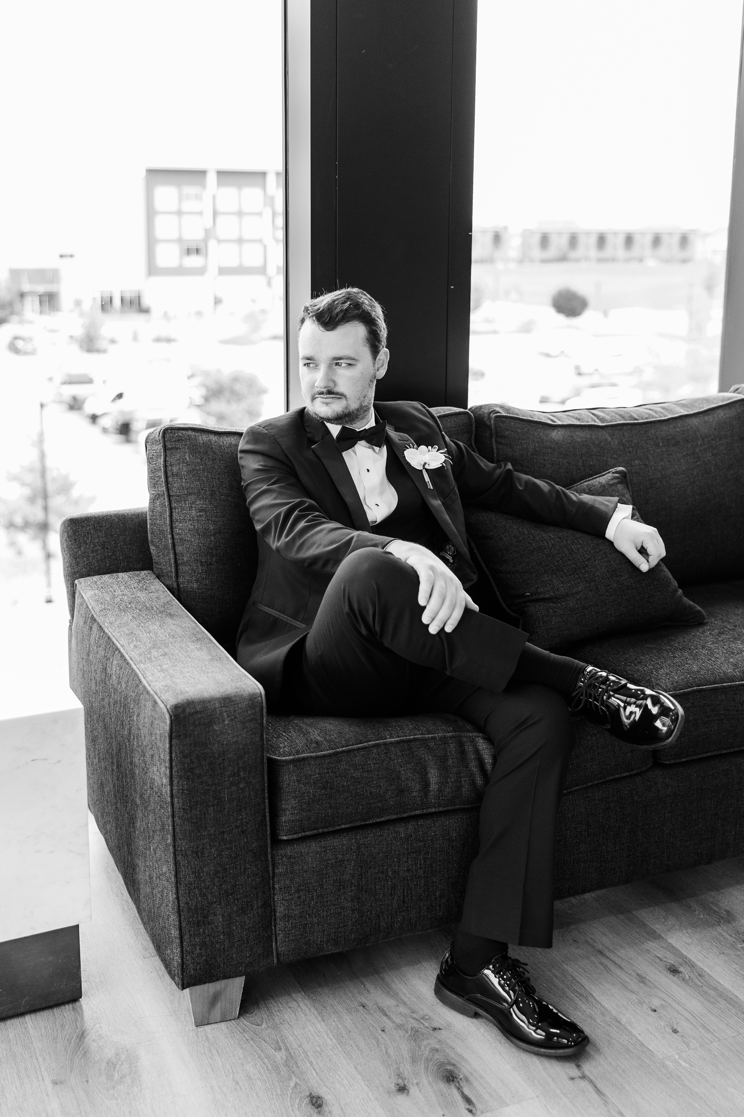 Grant sits stoically on a dark grey couch with his leg crossed over his knee as he looks to his right at Toast in Ankeny, IA | CB Studio