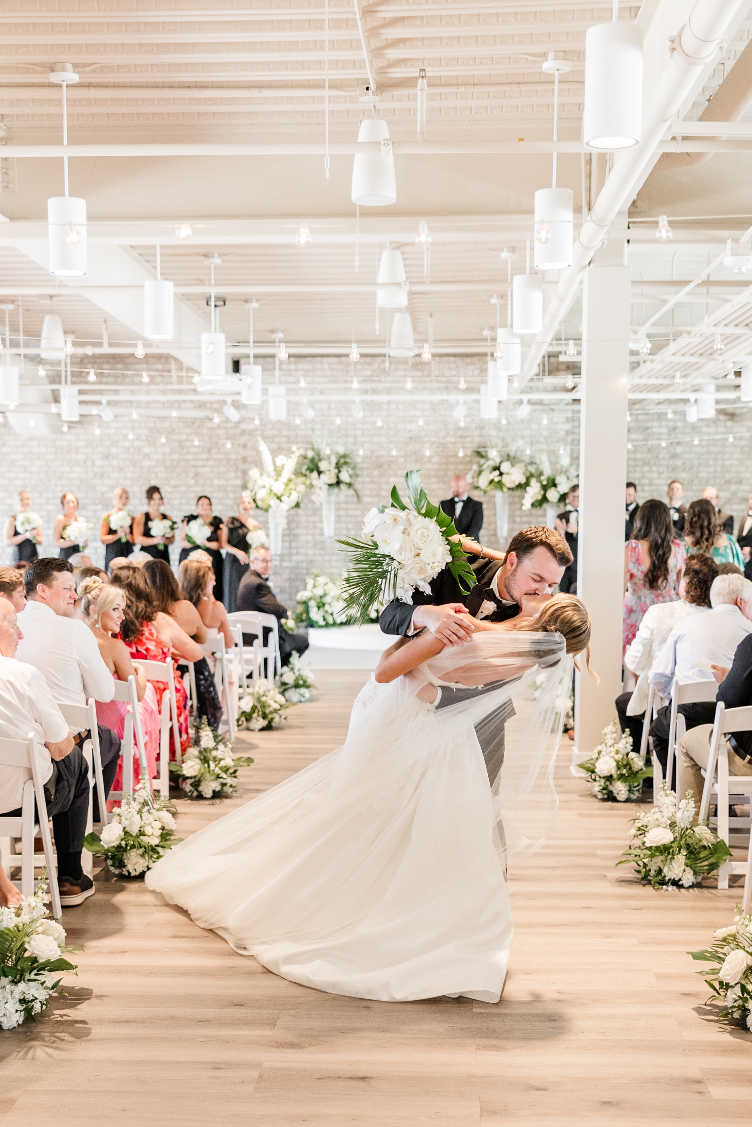 Grant dips his new wife, Cassidy, for a kiss as they walk down the aisle from their wedding ceremony at Toast in Ankeny, IA | CB Studio