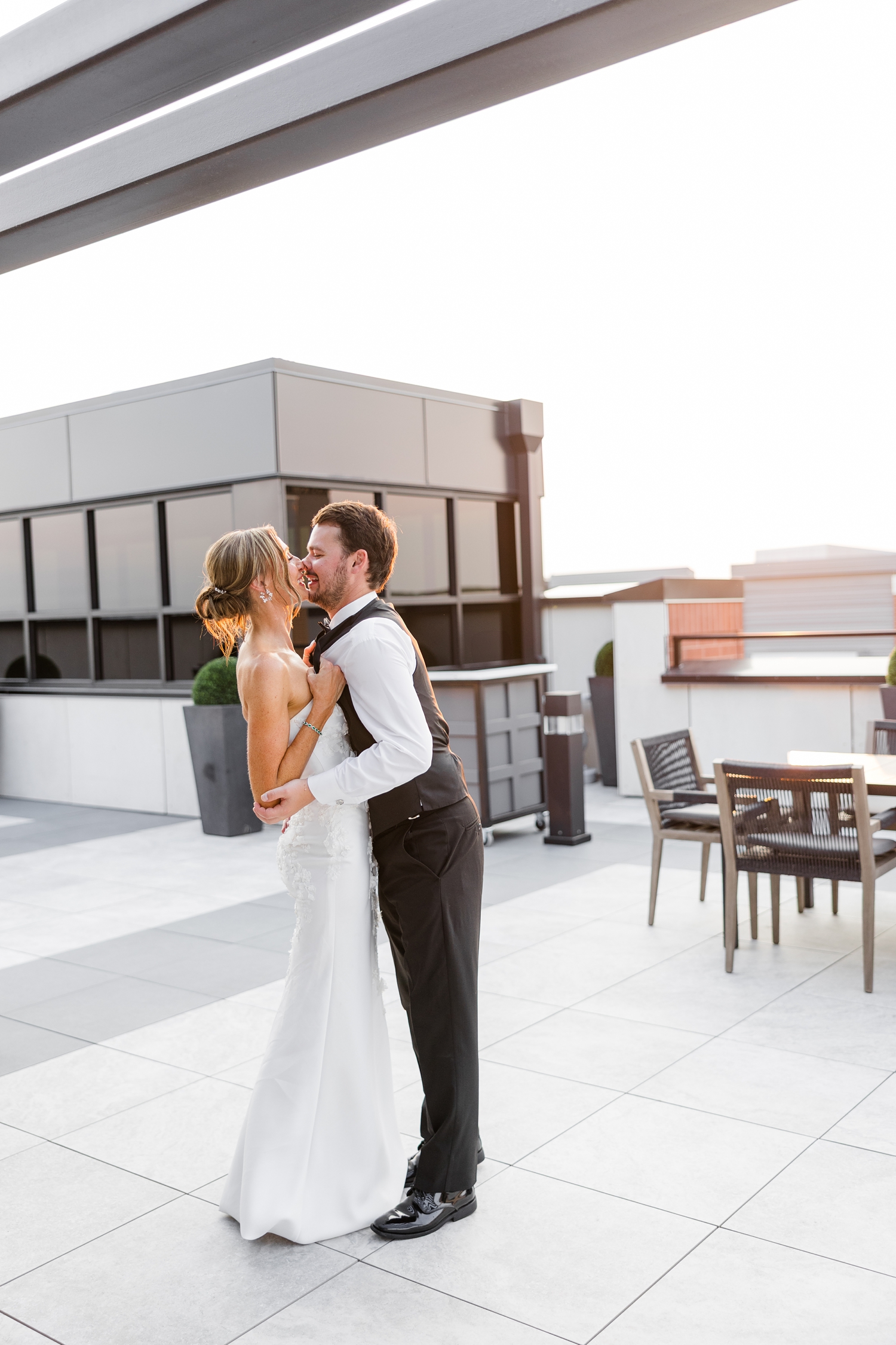 Cassidy pulls her new husband, Grant, in for a kiss as the laugh during sunset on the rooftop deck of Toast in Ankeny, IA | CB Studio