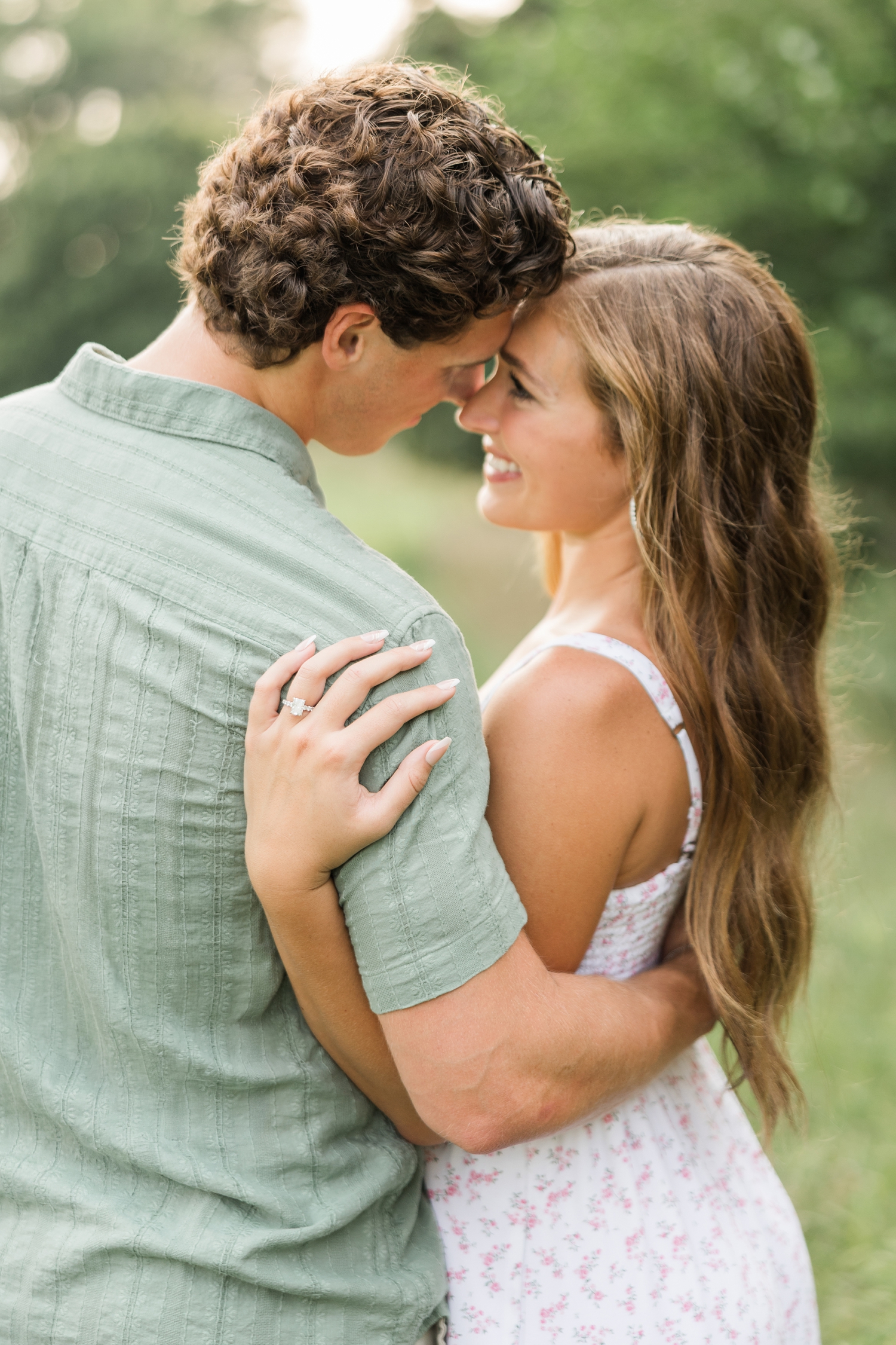 Deni wraps her arm around Tyler's back and shoulder as they rest foreheads together in a grass pasture | CB Studio