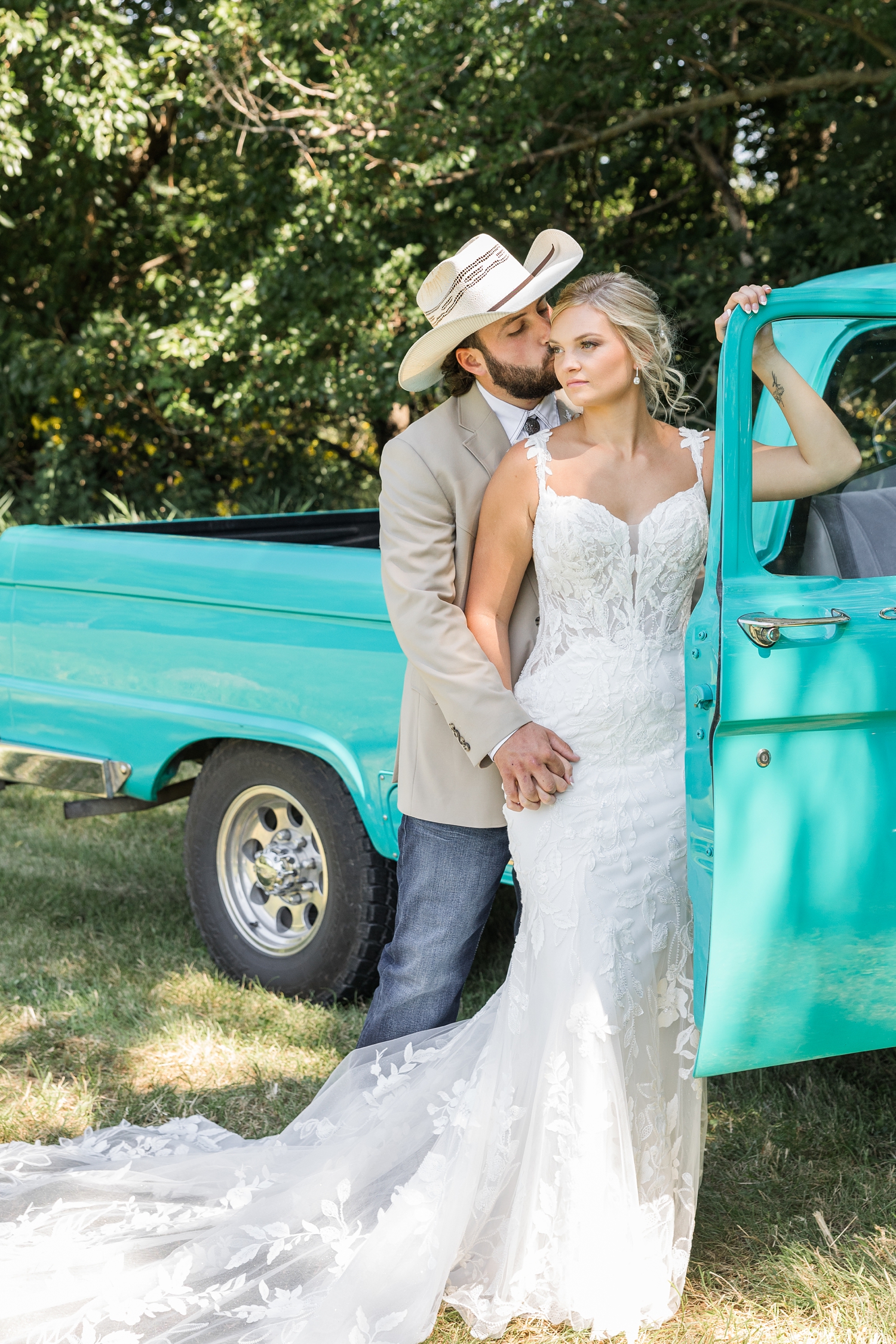 Jade leans on the open passenger side door of an old restore turquoise Ford truck as Dawson stands behind her, holds her hand and kisses her cheek | CB Studio