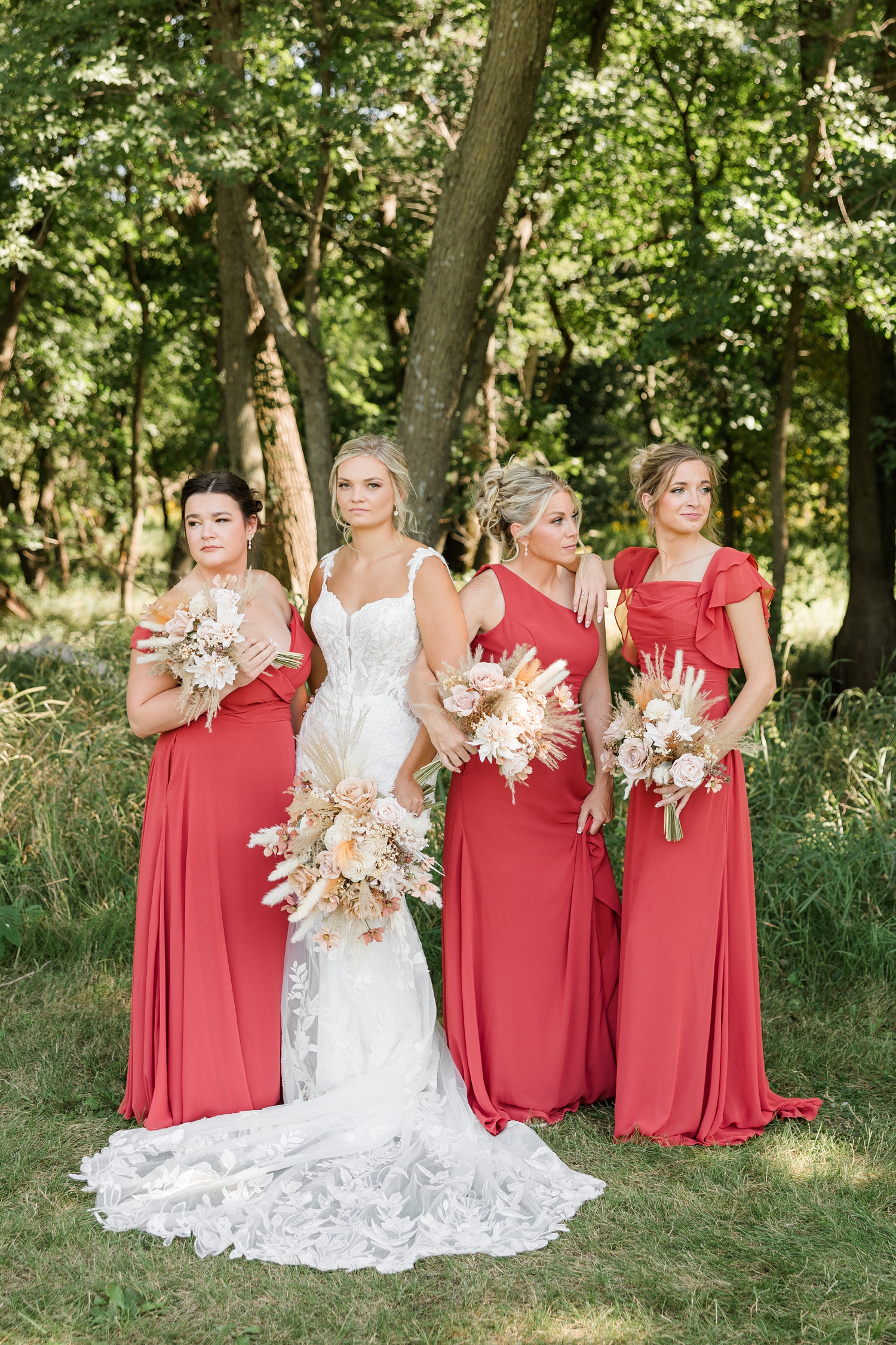 Jade and her bridesmaids (all wearing a red terracotta floor length dress) model pose as the bridesmaids look off into the distance on either side and Jade looks at the camera | CB Studio