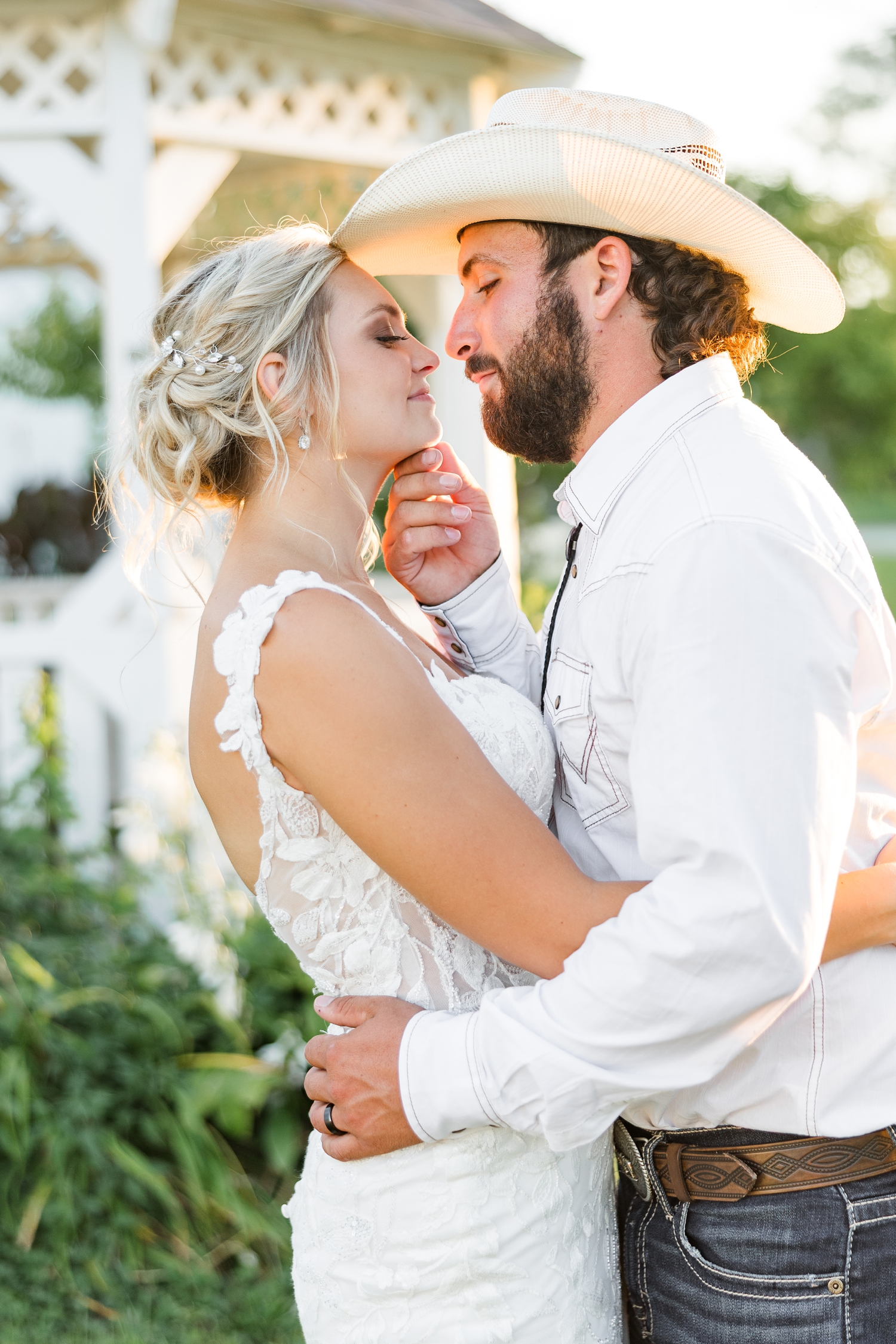 Dawson gently holds his bride's, Jade, chin and pulls her in slowly for a kiss at golden hour in front of a white gazebo | CB Studio
