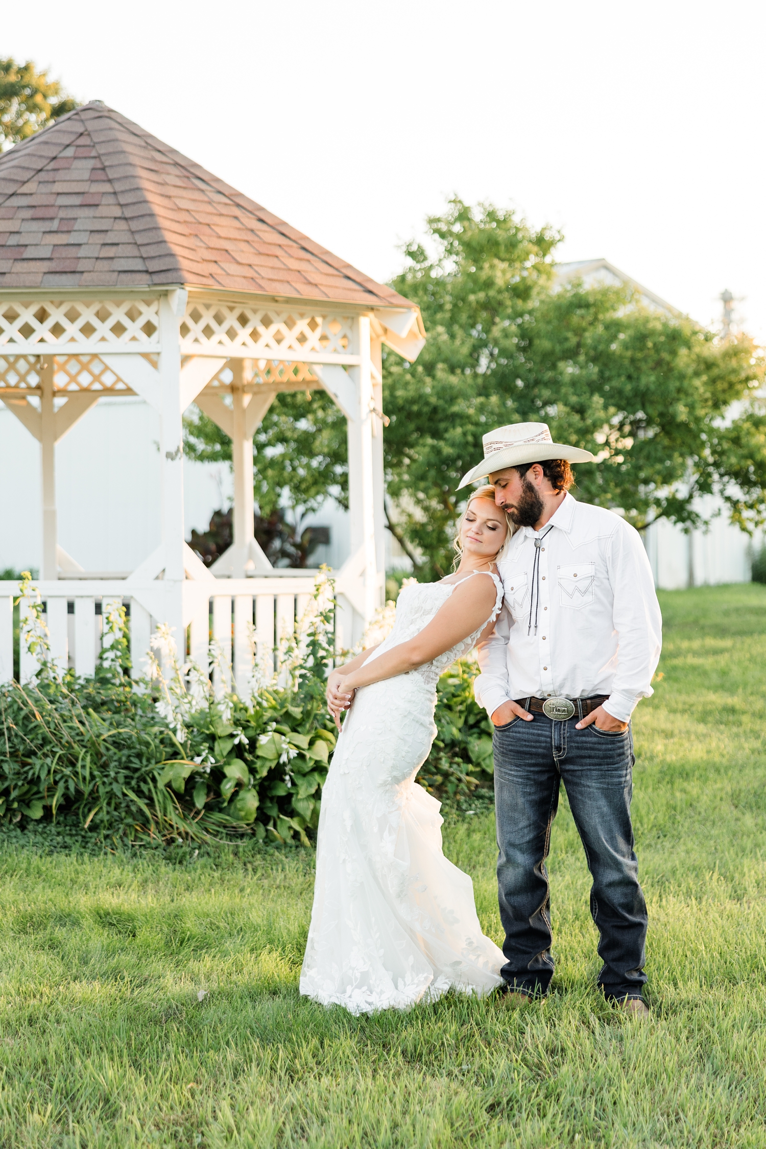 Jade leans back on Dawson's shoulder as she looks down and he looks at her with a white gazebo in the background | CB Studio