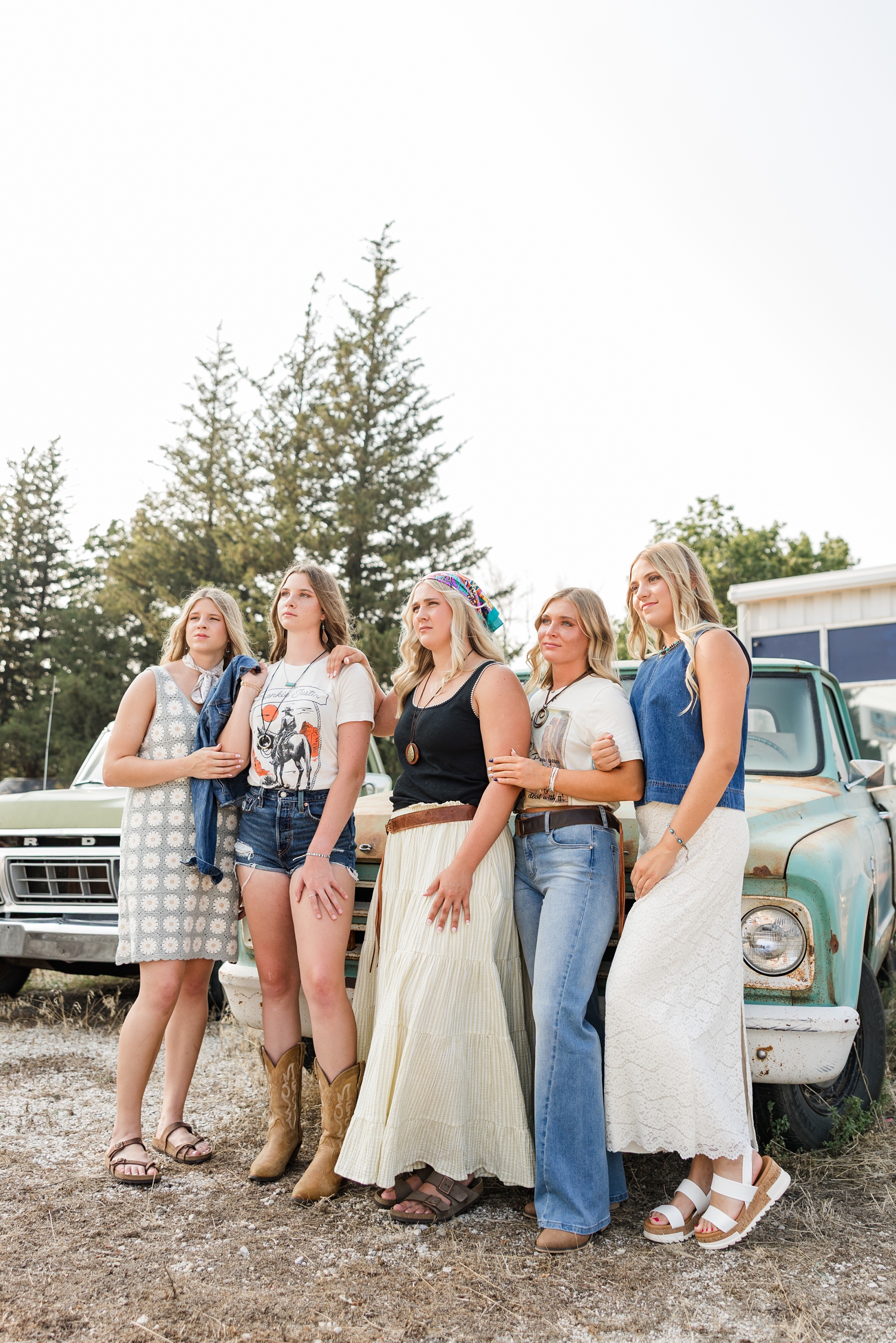 TEAM 27, dressed in boho, grunge looks, stand in model poses in front of an old rustic truck at a broken down gas station as they look off in the distance to the left | CB Studio