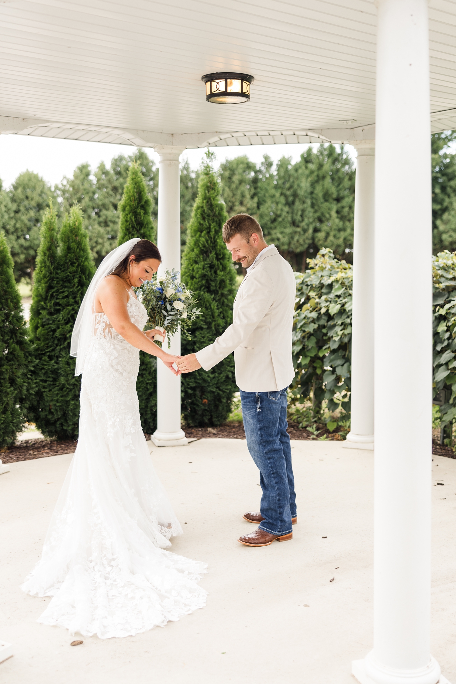 Ryan and Cassie look at her wedding gown underneath a white gazebo during their wedding day First Look | CB Studio