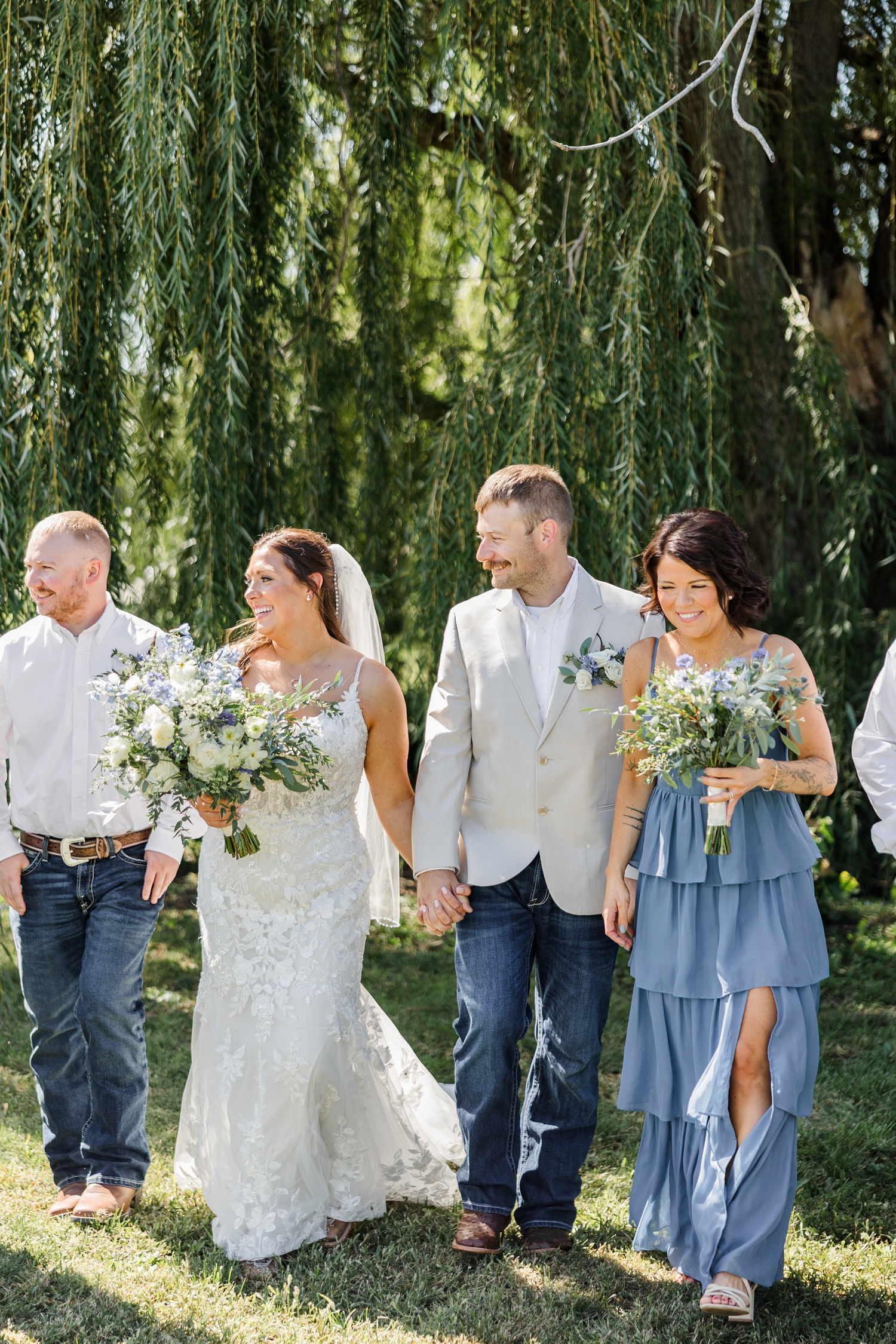 Ryan and Cassie walk with their wedding party smiling and laughing with a gorgeous weeping willow as the backdrop | CB Studio