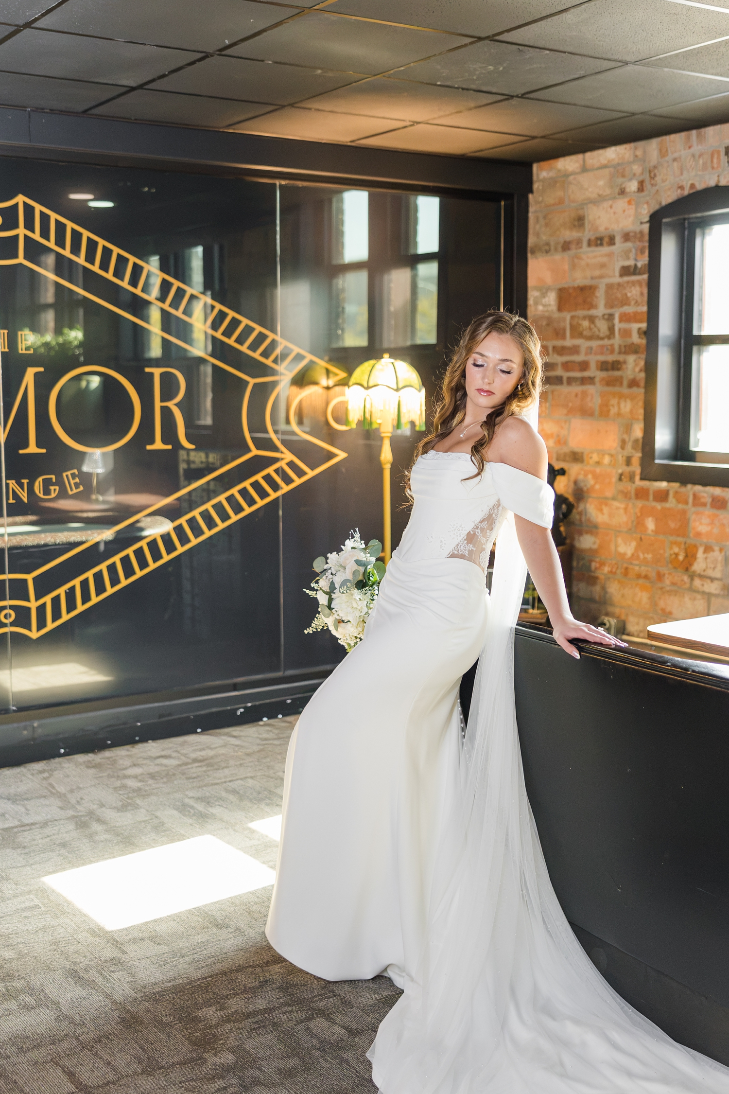 Bride model poses on the back of a couch in the speakeasy, Playmor Lounge, at the Laramar Ballroom in Fort Dodge, IA | CB Studio