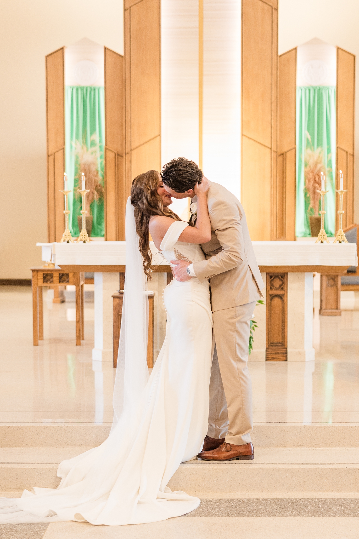 Bride and groom share their first kiss at the Holy Trinity Catholic Church in Fort Dodge, IA | CB Studio
