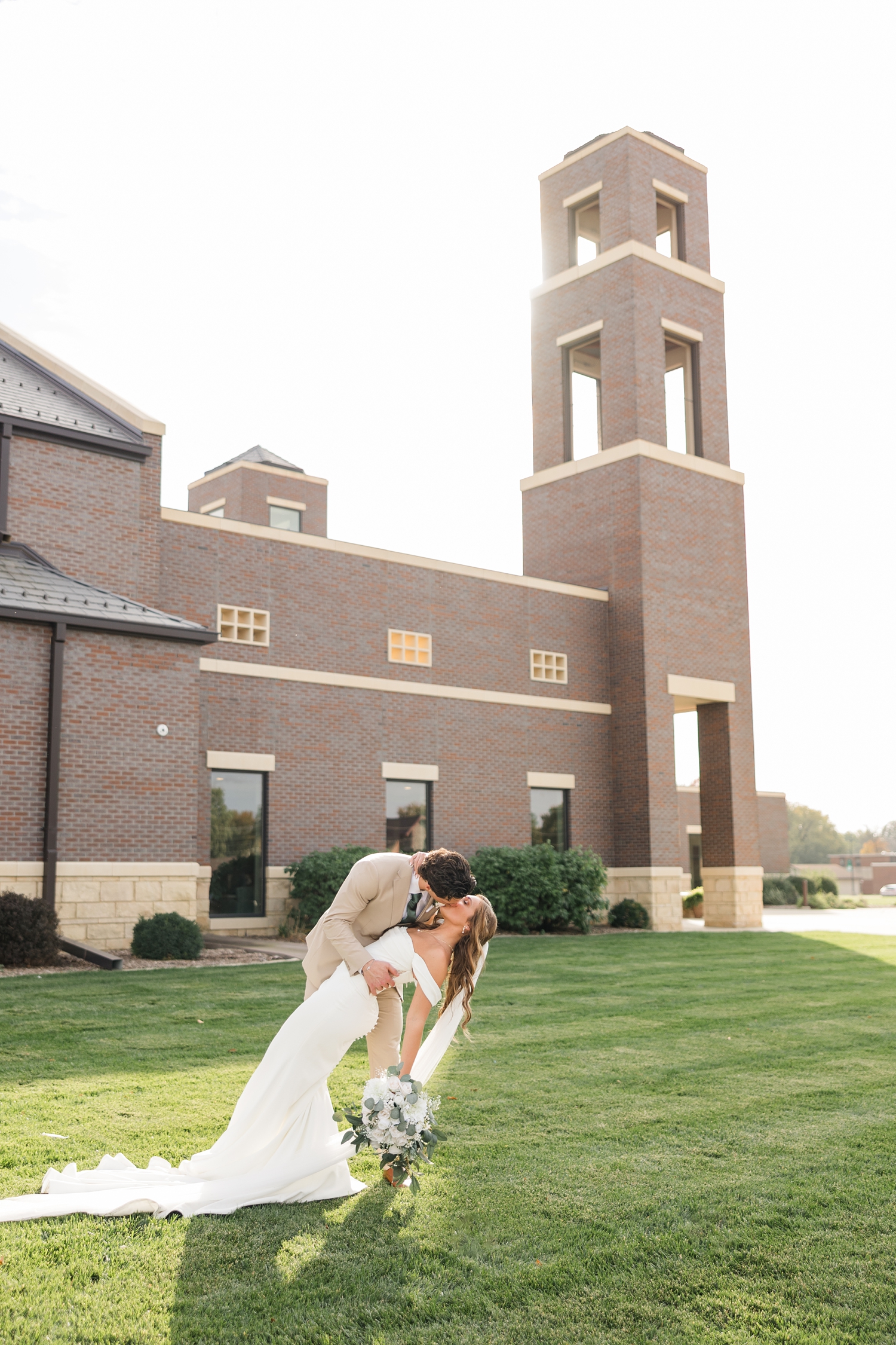 Groom dips his new bride for a kiss in front of the Holy Trinity Catholic Church in Fort Dodge, IA | CB Studio