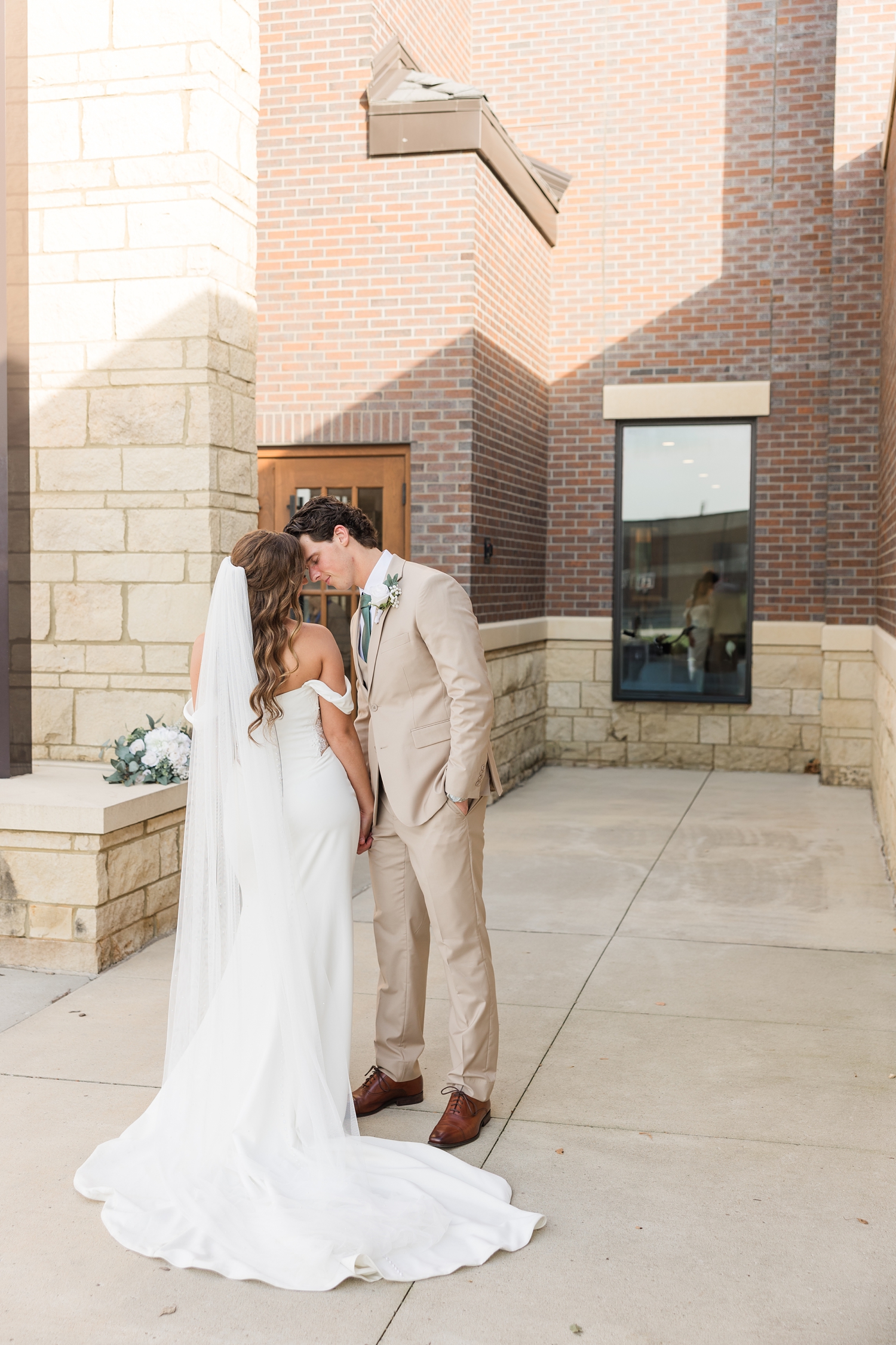 Bride and groom rest their foreheads together in front of the Holy Trinity Catholic Church in Fort Dodge, IA | CB Studio