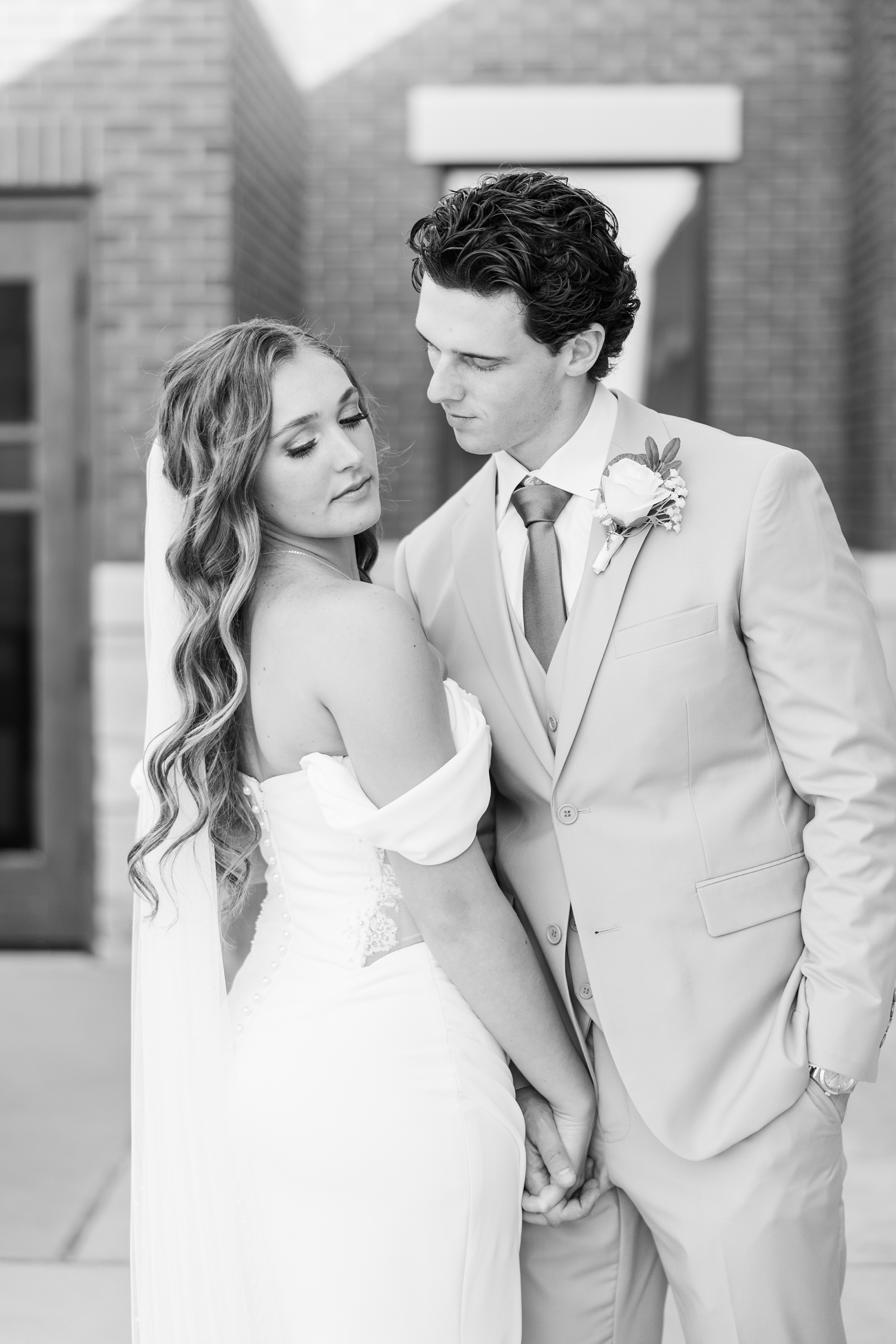 Groom looks intently at his bride as she looks back and down in front of the Holy Trinity Catholic Church in Fort Dodge, IA | CB Studio