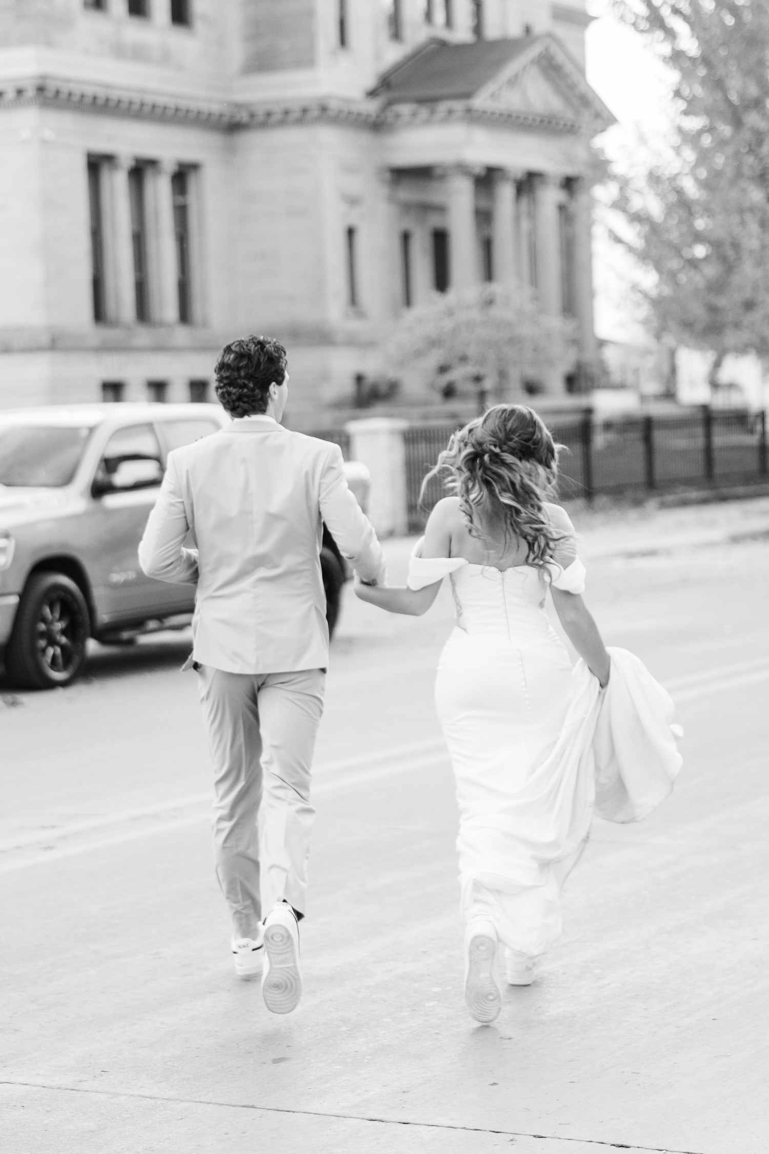 Bride and groom run together across a busy street in downtown Fort Dodge, IA | CB Studio