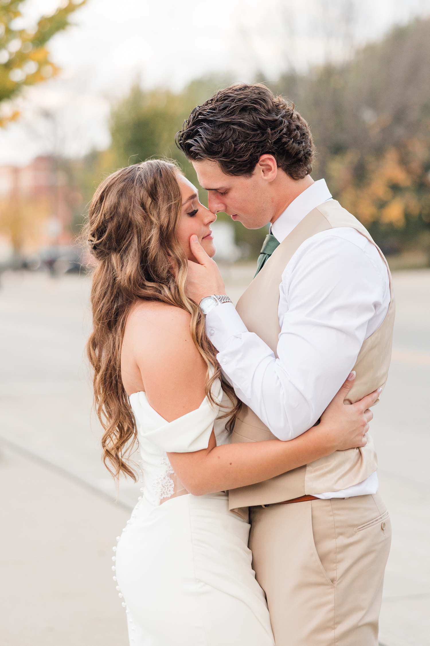 Bride and groom embrace closely as the groom gently holds the bride's cheek and they touch noses | CB Studio