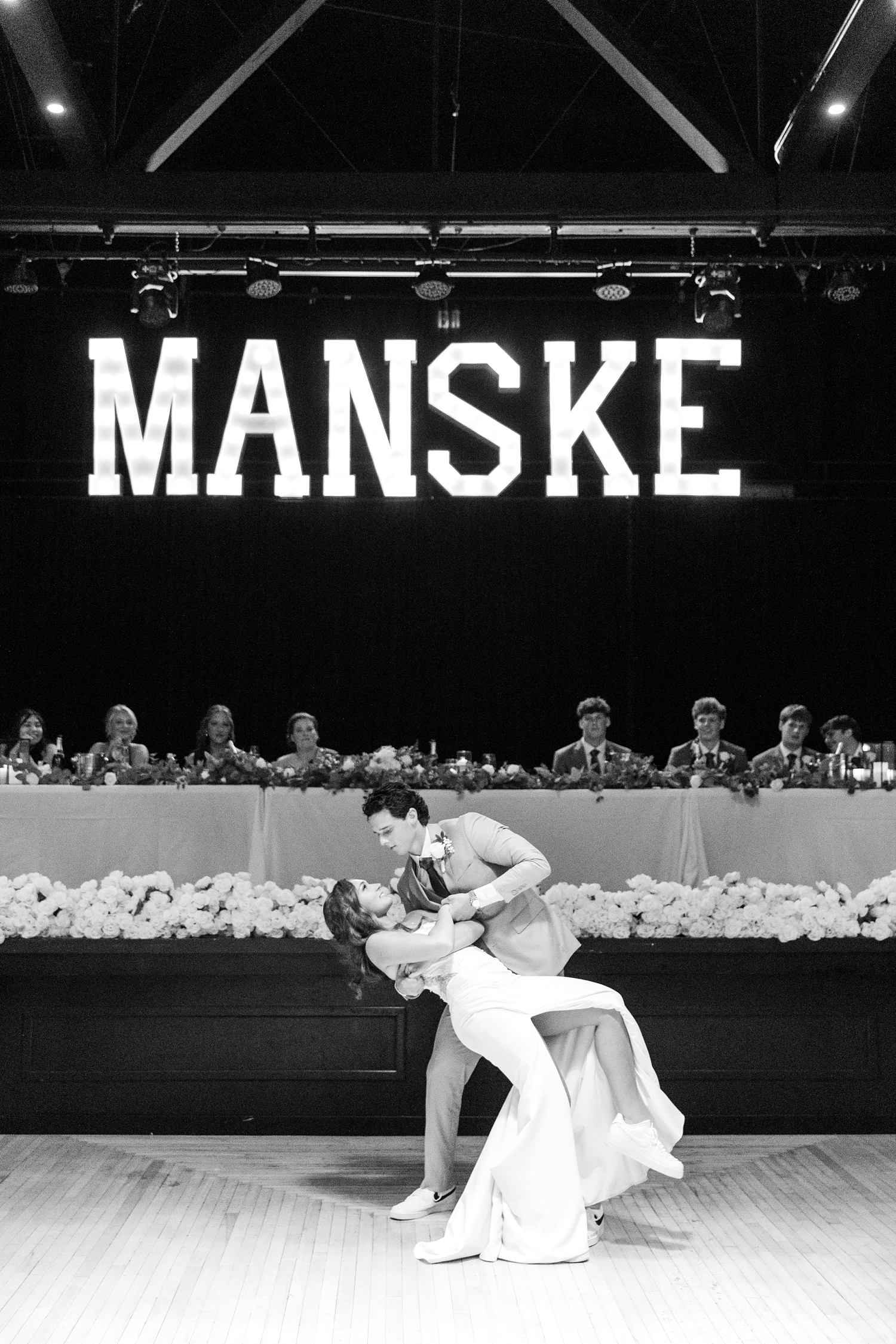 Tyler dips his new bride during their first dance together under a lighted sign of their last name at the Laramar Ballroom, Fort Dodge, IA | CB Studio