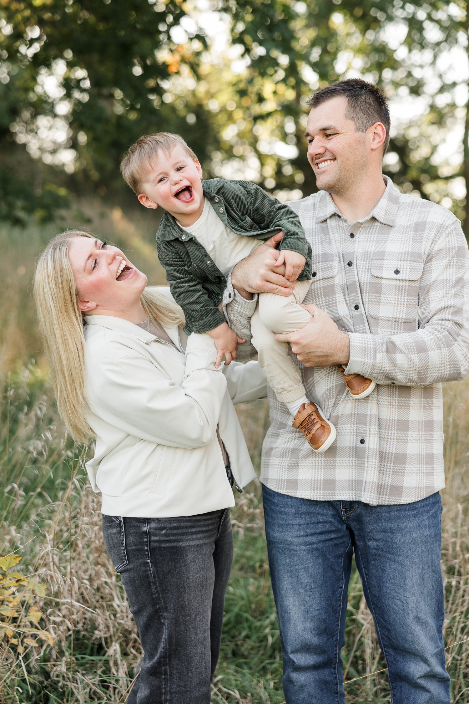 Cole holds his 2 year old son on one shoulder has the boy leans closer to mom while all are laughing | CB Studio